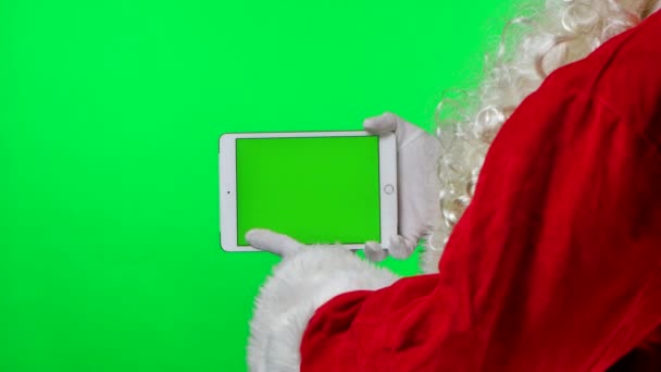 Side view Santa Claus with beard in white gloves uses tablet in horizontal position with green screen chroma key. Isolated on green background in the studio. Mock up display. Close up. Slow motion. — Stock Video