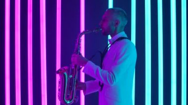 Beyaz takım elbiseli genç bir adamın saksafonu ustaca çalarkenar görüşü. Müzisyen, karanlık bir stüdyoda parlak neon ışıkların arkaplanına karşı bir konser veriyor. Ağır çekim, yakın çekim..