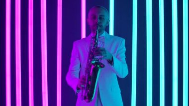 Beyaz takım elbiseli bir adam saksafonda beste yapıyor. Bir adam bir enstrüman çalar ve stüdyoda bir saksafonun ritmiyle neon boruların arka planına karşı dans eder. Yaklaşın, yavaşça.