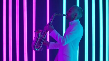 Beyaz takım elbiseli genç bir adamın saksafonu ustaca çalarkenar görüşü. Müzisyen, karanlık bir stüdyoda parlak neon ışıkların arkaplanına karşı bir konser veriyor. Ağır çekim, yakın çekim..