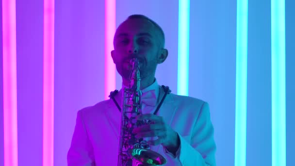 Mannelijke handen vingeren de sleutels van de saxofoon. Een saxofonist geeft een live concert in een donkere studio tegen de achtergrond van fel neonlicht. Sluit maar af. Langzame beweging. — Stockvideo