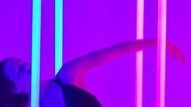Bir kadın renkli neon tüplerle aydınlatılmış bir stüdyoda çağdaş koreografi sergiliyor. Oyuncu kollarını duygusal bir dans hareketi ile kaldırır ve neon boruları yakalar. Yaklaşın, ağır çekim..
