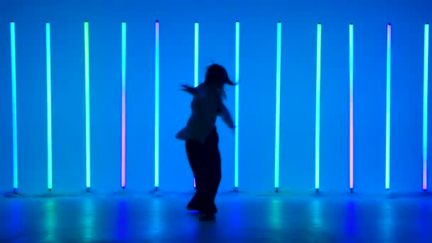 Młoda tancerka tańcząca w studio na tle wielobarwnych neonów. Utalentowana dziewczyna wykonuje taniec z elementami nowoczesności i baletu. Sylwetka. — Wideo stockowe