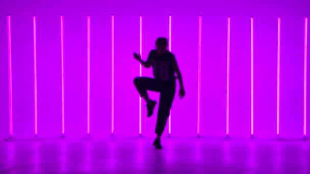 Çok renkli neon tüplerle aydınlatılmış bir stüdyoda dans eden genç bir kadın. Dansçı hip hop, serbest stil, dans salonu icra ediyor. Koyu renk siluet. — Stok video