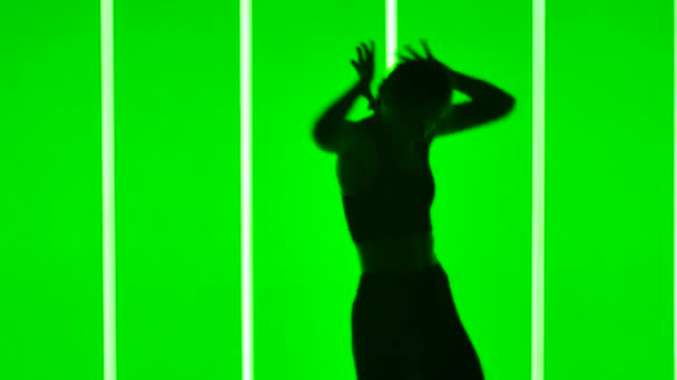 Jonge vrouw dansen straat hip hop dans in de studio tegen de achtergrond van heldere neon buizen. Een hip hop danser die moderne bewegingen uitvoert in slow motion. Donker silhouet. Sluiten.. — Stockvideo