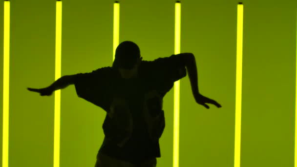 Stylischer Typ, der Hip-Hop tanzt. Zeitgenössischer Tanz im freien Stil im Studio vor der Kulisse heller Neonlichter. Straßentanz als Lebensform. Silhouette. Aus nächster Nähe. Zeitlupe. — Stockvideo