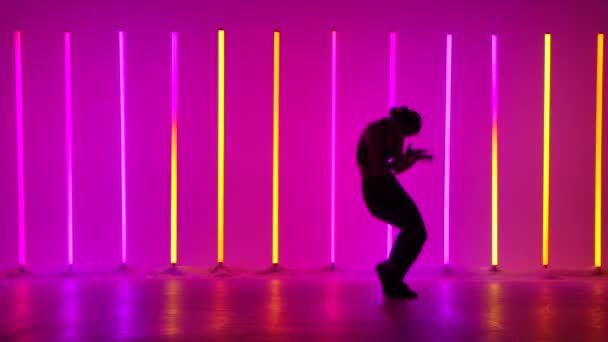 Çok renkli neon tüplerle aydınlatılmış bir stüdyoda dans eden genç bir kadın. Dansçı hip hop, serbest stil, dans salonu icra ediyor. Koyu renk siluet. Yavaş çekim. — Stok video