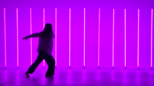明るいネオンに照らされたスタジオで柔軟なプロの女性ダンス。女性がスローモーションでストリートダンスを披露します。シルエット. — ストック動画