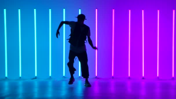 Dans eden ve çağdaş koreografi yapan şık bir gencin silueti. Parlak, renkli neon ışıklar arasında sokak dansı. Yavaş çekim. — Stok video