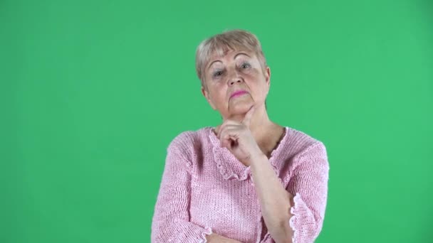 Portrait femme âgée pensant avec concentration heureux il ya une idée. Grand-mère aux cheveux gris avec les cheveux courts dans un pull rose sur l'écran vert au studio. Gros plan. — Video