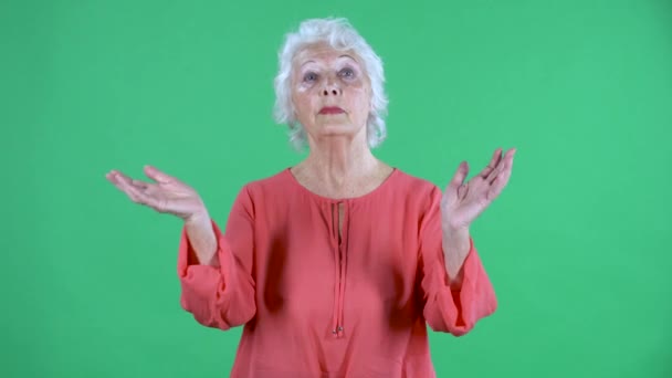Portrait einer älteren Frau, die in die Kamera schaut und freudig in die Hände klatscht. Grauhaarige Großmutter in roter Bluse auf grünem Bildschirm im Studio. Nahaufnahme. — Stockvideo