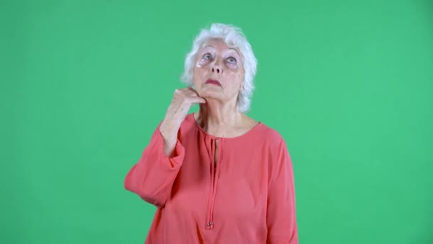 Ritratto donna anziana che pensa con concentrazione. Nonna dai capelli grigi in camicetta rossa su schermo verde a studio. Da vicino.. — Video Stock