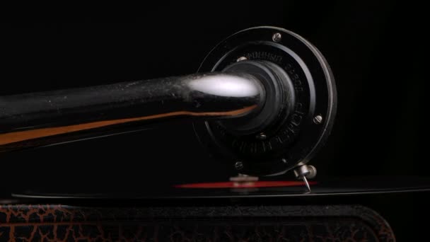 Large needle of a vintage gramophone on rotates vinyl record. Vintage musical instrument on a black studio background. Nostalgia. Retro turntable close up. Detailed macro shooting. Slow motion. — Stock Video