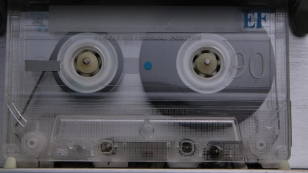 En ljudkassett spolar tejp i extrem makro. Vintage musik kassett spelar upp i spelaren. Närbild. Långsamma rörelser. — Stockvideo