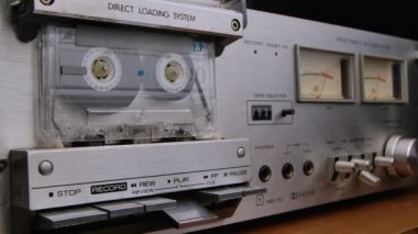 Eski, pejmürde bir ses kasedi bir teypte dönüyor. Klasik bir kayıt cihazının detaylı makro görüntüsü. 90 'ların nostaljik müziğini dinliyorum. Kapatın. Yavaş çekim.