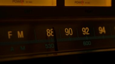 Sarı vintage radyo alıcısı ve fm ölçekli amplifikatör. Analog radyo frekansı retro alıcının ölçeğine göre ayarlanıyor. Eski radyodaki istasyonları arıyorum. Kapatın. Yavaş çekim.