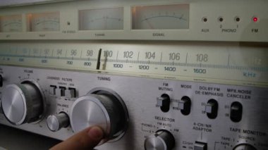 Klasik radyo alıcısı ve fm ölçekli yükseltici. Erkek el ayarı analog radyo frekansı retro alıcının ölçeğinde. Eski radyodaki istasyonları arıyorum. Kapatın. Yavaş çekim.