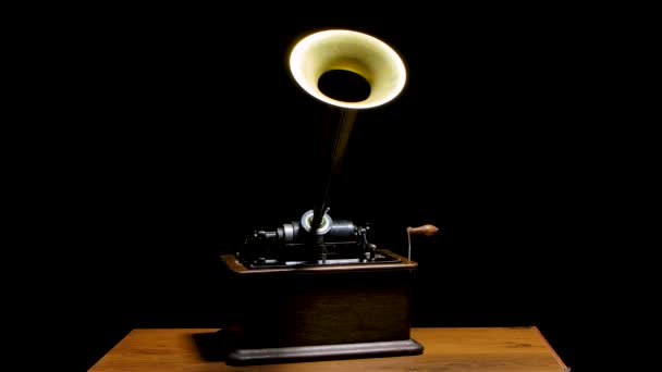 Phonograph clásico de Edison en una mesa de madera en un estudio oscuro. Máquina retro vintage para reproducir sonido haciendo escuchar música. Movimiento lento. — Vídeo de stock