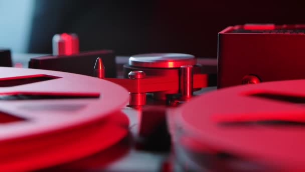 Reel to reel tape recorder playing. Rotating vintage music player close up illuminated by red neon lights. Spinning reels metallic color. Retro party. Popular Disco Trends 70s, 80s. Side view. — Stock Video