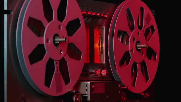 老式专业模拟卷筒到卷筒磁带录音机，由红色霓虹灯照明。卷轴在动，唱片在放，音乐在放。靠近点. — 图库视频影像