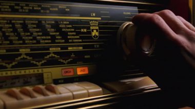Erkek eli, klasik radyo alıcısını müzik veya haber dinlemek için ayarlıyor. Eski bir radyonun ön paneli, kapatın..