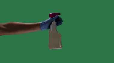Mavi koruyucu eldivenli bir adamın silueti bir sprey şişesi tutuyor ve Covid 2019 Corona virüsünü dezenfekte etmek için dezenfektan alkol püskürtüyor. Yeşil ekran, krom anahtar. Ağır çekim. Kapat