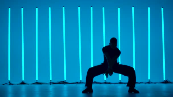 Donker silhouet van een jongeman die danst langs rijstroken. Een professionele ballroomdanser oefent de rumba-elementen in de studio tegen de achtergrond van felgekleurde neonlichten. Langzame beweging. — Stockvideo