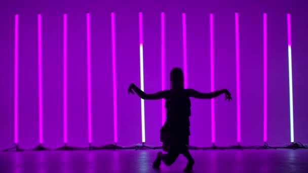Тёмный силуэт молодой женщины, танцующей латинский танец. Профессиональный танцор танцует румбу, ча ча ча ча или самба в студии на фоне ярких разноцветных неоновых ламп. Медленное движение. — стоковое видео