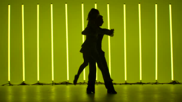 Deux danseurs dansent une danse latino-américaine passionnée. Rumba, samba, cha cha cha, jive. Silhouettes sombres de danseurs sur fond de lampes au néon multicolores lumineuses. Mouvement lent. — Video