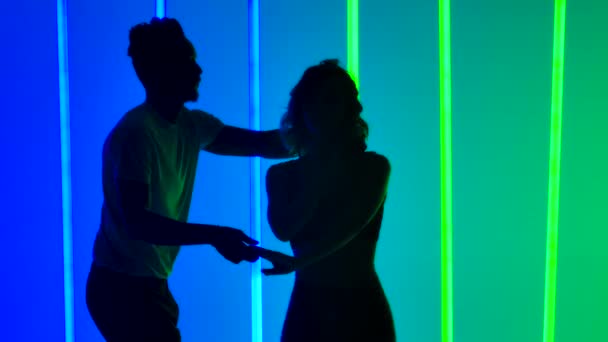 Dançarinos profissionais dançando salsa no estúdio contra o pano de fundo de luzes de néon multicoloridas em câmera lenta. O conceito de amor, relacionamentos e dança social. Silhuetas. Fechar. — Vídeo de Stock