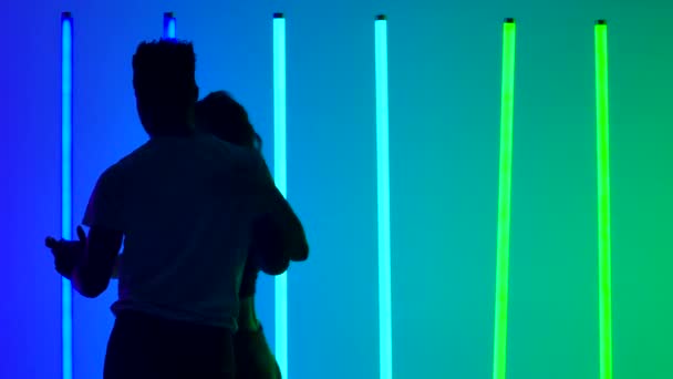 Hete dans van twee professionele dansers, slow motion. Silhouetten van dansende man en vrouw in de studio tegen een achtergrond van felgekleurde neonlichten. Sluiten.. — Stockvideo