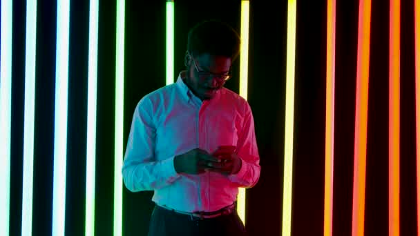 Portrét mladého stylového muže Afroameričana, který se usmívá a píše sms na smartphonu. Zpomalený pohyb. — Stock video