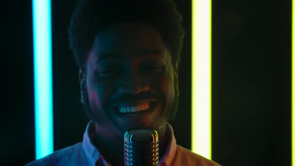 Portrait d'un jeune homme élégant souriant afro-américain chante dans un microphone rétro et danse joyeusement. Ferme là. Mouvement lent. — Video