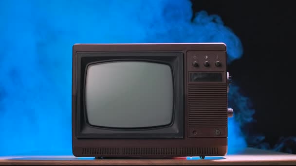 Stílus retro TV készlet kapcsolókkal. Régimódi tévé füstös stúdió háttérrel, kék neon fényekkel. Lassú mozgás.. — Stock videók
