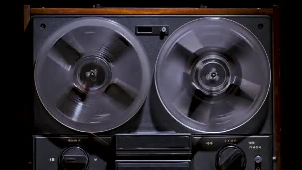 Male hands include rewind on vintage reel to reel tape recorder against a black studio background. Retro music player. Front view close up. Popular disco trends 70s, 80s. Slow motion. — Stock Video