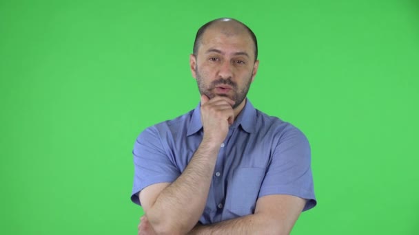 Portret van een man van middelbare leeftijd die aandachtig luistert, is geschokt en erg van streek. Kalende man met baard in blauw shirt poserend op groen scherm in de studio. Sluiten.. — Stockvideo