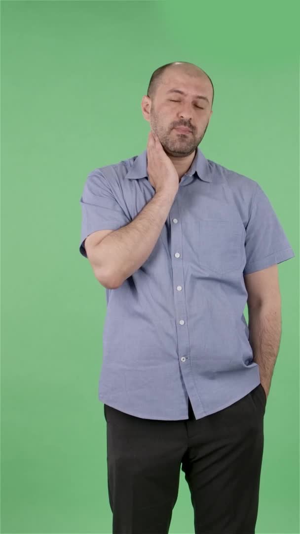 Portrait d'un homme d'âge moyen regardant la caméra secouant la tête, exprimant son innocence. Homme chauve avec barbe en chemise bleue posant sur écran vert en studio. Au ralenti. Vidéo verticale. — Video