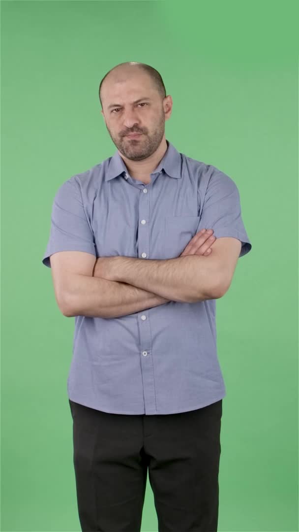 Портрет чоловіків середнього віку засмучений і втомився. Оболонка чоловічої статі з бородою в синій сорочці позує на зеленому екрані в студії. Повільний рух. Вертикальне відео . — стокове відео