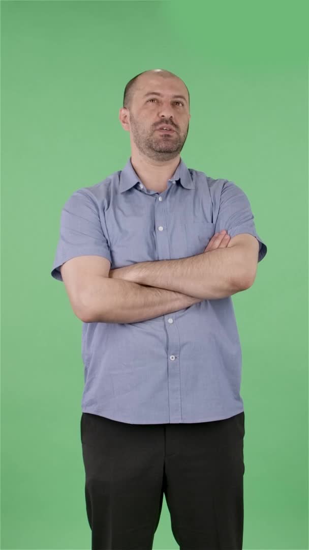 Portrait of a middle aged men looking at camera telling interesting information and gesturing with his hands. Balding male with beard posing on green screen in the studio. Slow motion. Vertical video. — Stock Video