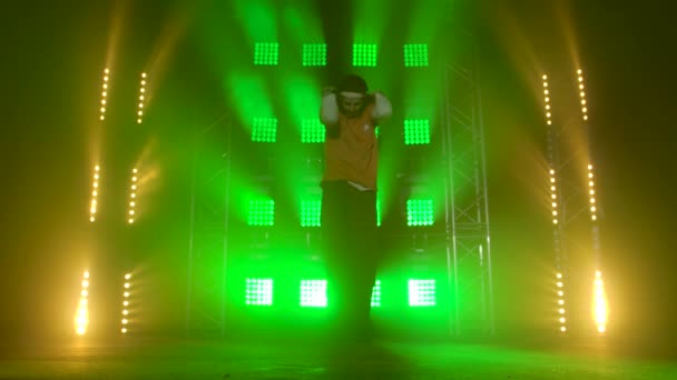 Profesyonel genç hip-hop dansçısı, yeşil ve sarı siste karanlık stüdyoda dans ediyor. Hip hop kültürü. Prova. Çağdaş. — Stok video