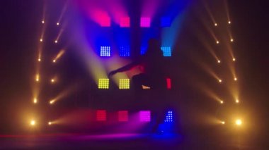 Profesyonel genç hip-hop dansçısı, yeşil ve sarı siste karanlık stüdyoda dans ediyor. Hip hop kültürü. Prova. Çağdaş.