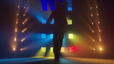 Profesyonel genç hip-hop dansçısı, yeşil ve sarı siste karanlık stüdyoda dans ediyor. Hip hop kültürü. Prova. Çağdaş.