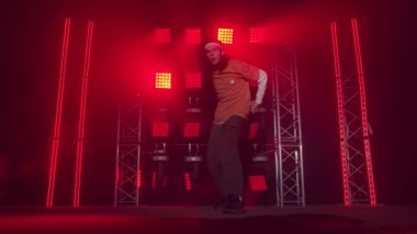 Profesyonel genç hip-hop dansçısı, yeşil ve sarı siste karanlık stüdyoda dans ediyor. Hip hop kültürü. Prova. Çağdaş.