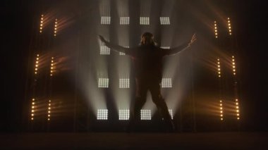 Profesyonel genç hip-hop dansçısı, yeşil ve sarı siste karanlık stüdyoda dans ediyor. Hip hop kültürü. Prova. Çağdaş.