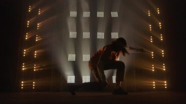 Profesyonel genç hip-hop dansçısı, yeşil ve sarı siste karanlık stüdyoda dans ediyor. Hip hop kültürü. Prova. Çağdaş.