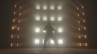 Profesyonel genç hip-hop dansçısı, yeşil ve sarı siste karanlık stüdyoda dans ediyor. Hip hop kültürü. Prova. Çağdaş.
