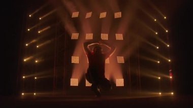 Profesyonel genç hip-hop dansçısı, yeşil ve sarı siste karanlık stüdyoda dans ediyor. Hip hop kültürü. Prova. Çağdaş.