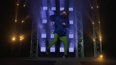 Yetenekli genç bir hip hop dansçısının silueti. Karanlık bir stüdyoda, dumanlı ve neon ışıklı bir sahnede hip hop sokak dansı. Dinamik ışıklandırma efektleri. Yaratıcı yetenekler. Yavaş çekim.