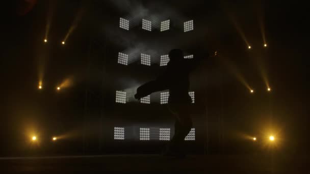才能ある若いヒップホップダンサーのシルエット。煙とネオンの照明と暗いスタジオでステージ上のヒップホップストリートダンス。ダイナミックな照明効果。創造的なスキル。スローモーション. — ストック動画