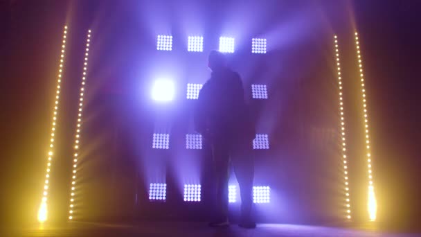 Σιλουέτα ενός ταλαντούχου νεαρού χορευτή χιπ χοπ. Hip hop street dance σε μια σκηνή σε σκοτεινό στούντιο με καπνό και νέον φωτισμό. Δυναμικά εφέ φωτισμού. Δημιουργικές ικανότητες. Αργή κίνηση. — Αρχείο Βίντεο